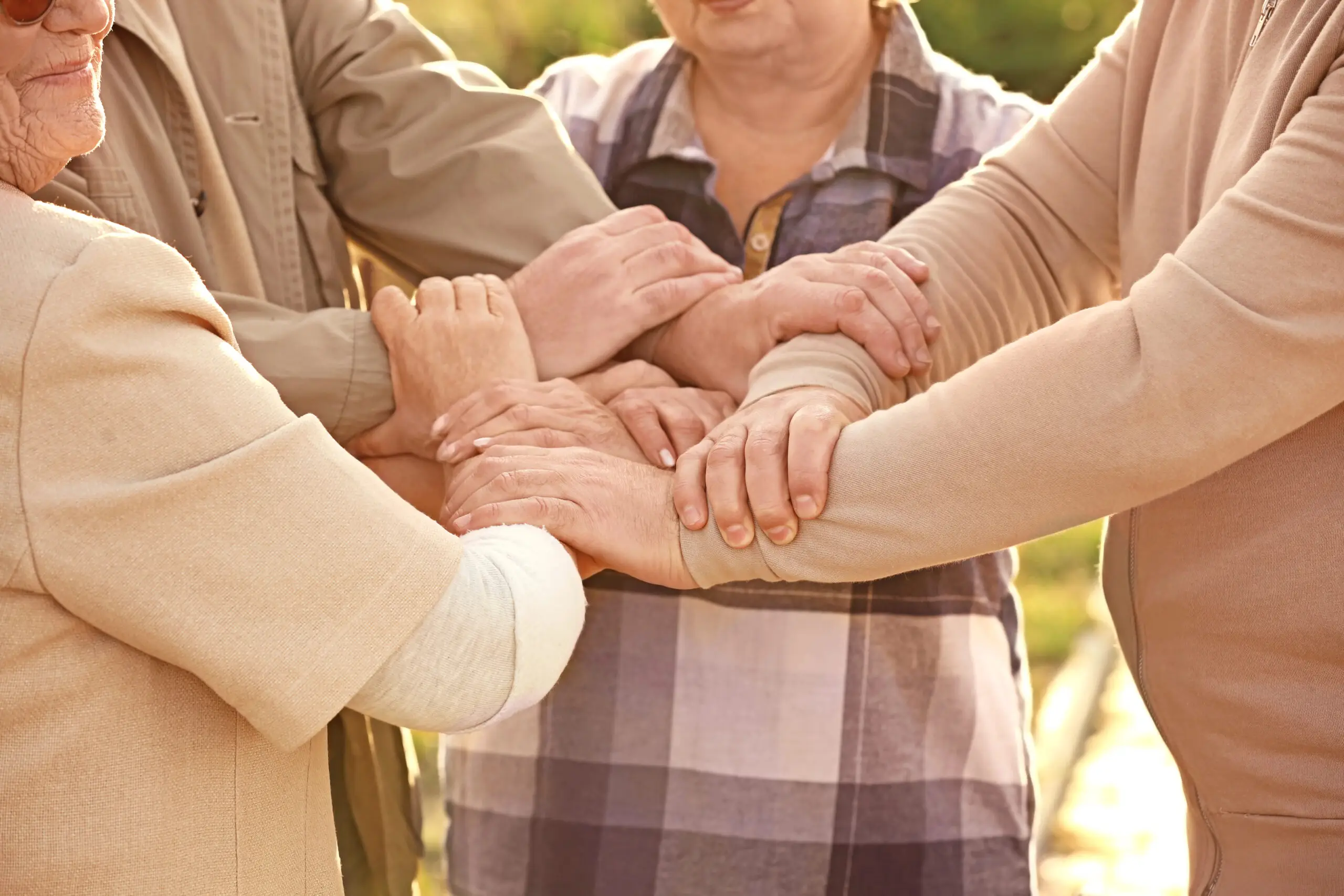 Seniorzy trzymają dłonie razem w geście wsparcia, bliskości i integracji