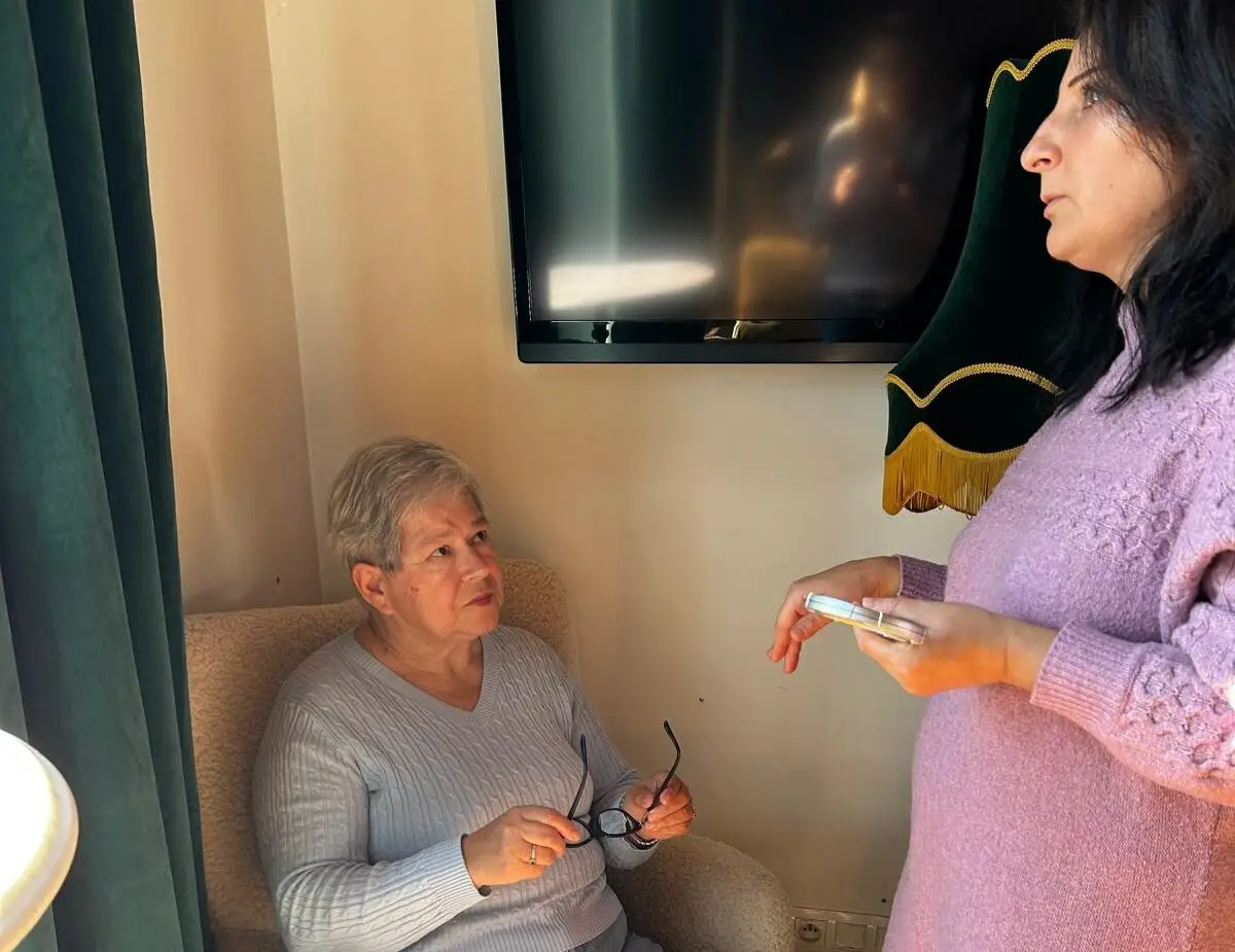 Seniorka siedzi w fotelu i rozmawia z prowadzącą podczas indywidualnego spotkania w Klubie